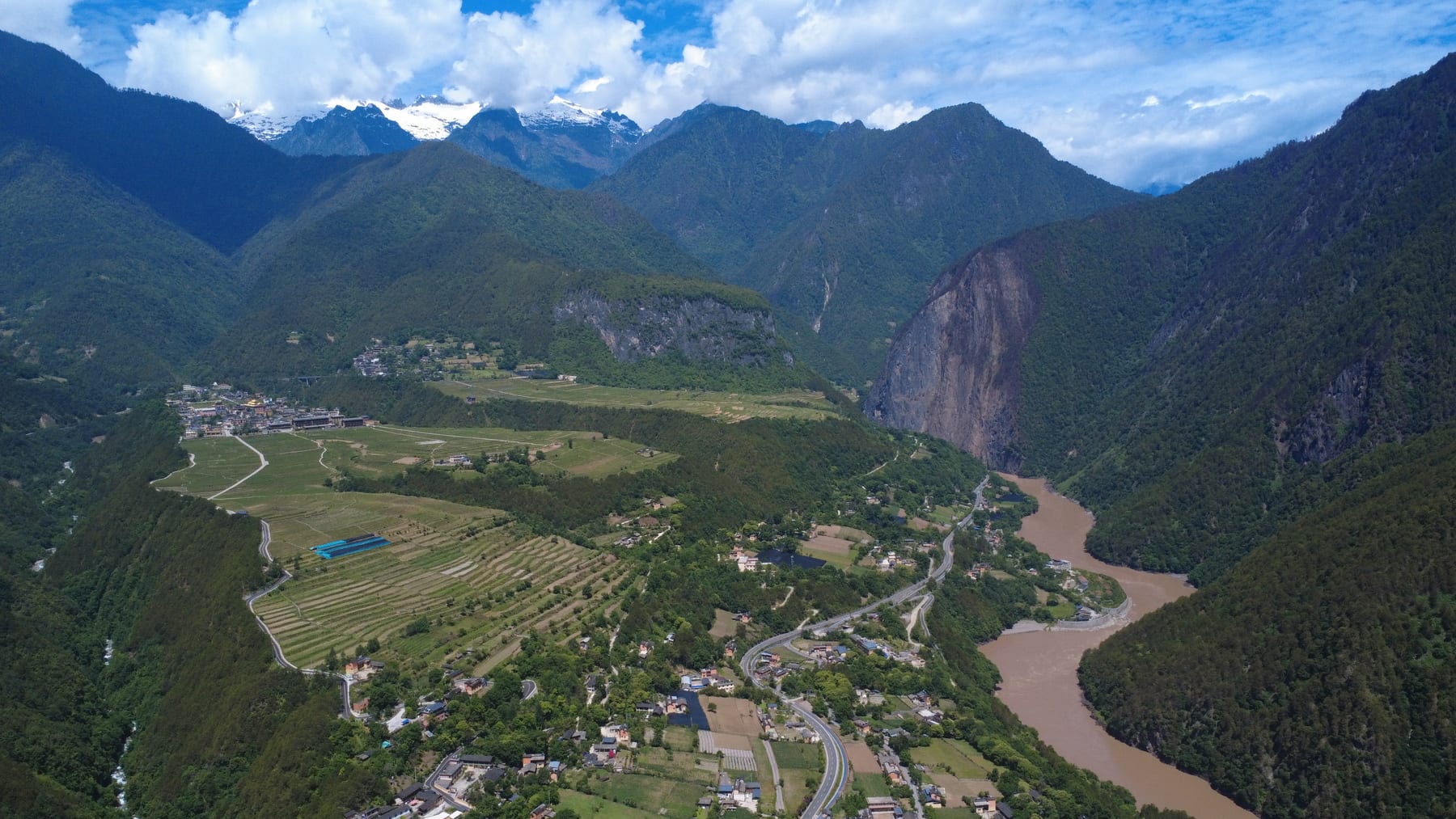 The Bingzhongluo basin from the air, farmland and villages below snow peaks, the Nu River in its gorge