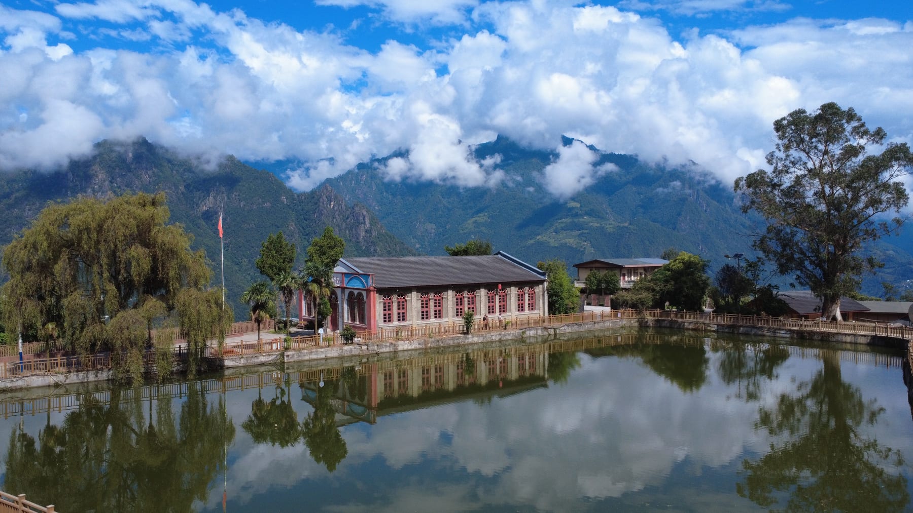Laomudeng's church beside its village pond, cloud on the ridges behind