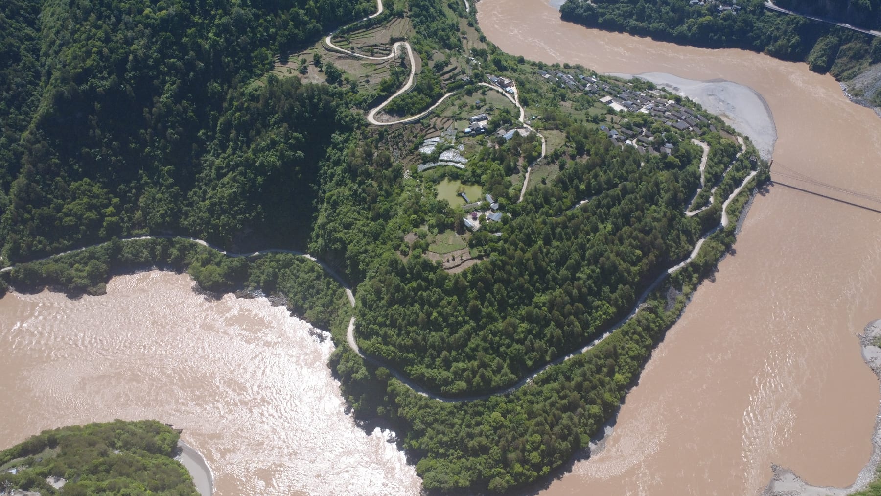 The Nu River's First Bend at Bingzhongluo from the air, the river looping around a forested peninsula