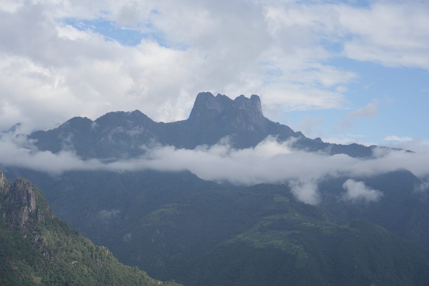 The rock crown of Huangguan Shan rising above the clouds on the far side of the Nujiang gorge