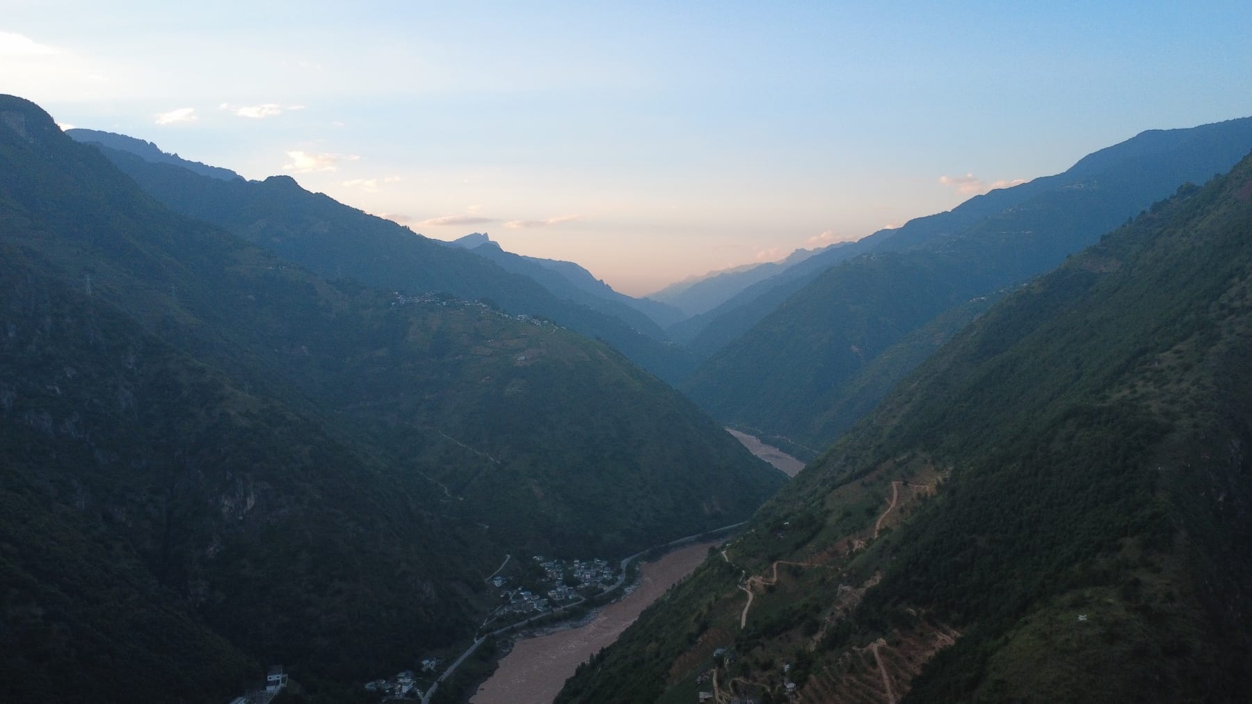 Dusk over the Nu River valley in Fugong county, the river winding between dark ridges under a pink sky