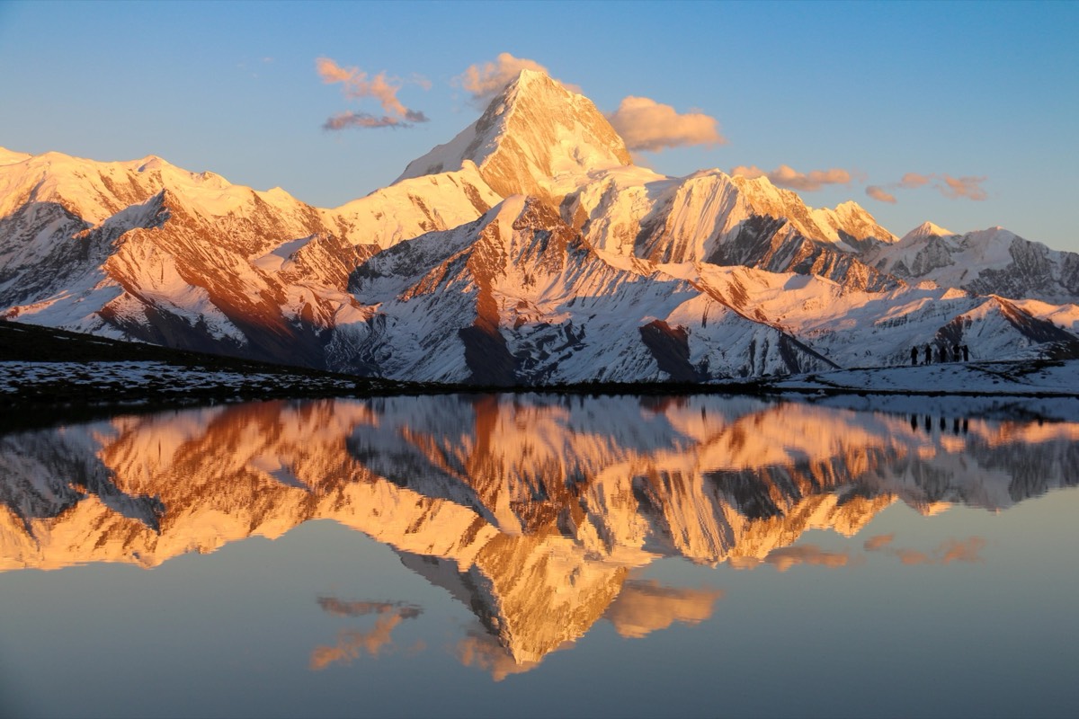 Lengga Cuo at golden hour — Chenrezig Peak reflected in a lake so still it breaks your brain. At 4,500m, the air is thin, the light lasts minutes, and the silence is absolute. Those tiny silhouettes on the right? That's what getting here looks like.