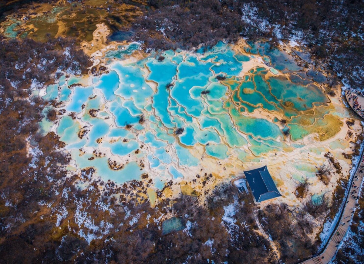 A high-angle shot of the mineral terraces in winter, where the bright blue water contrasts against t