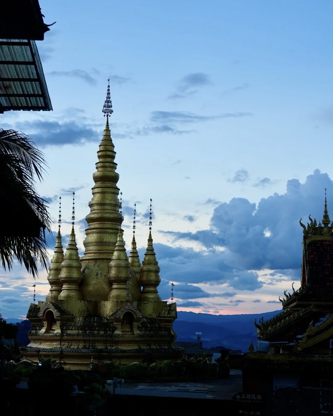Golden Buddhist stupa at dusk above the tea forests of Mangjing, Jingmai Mountain