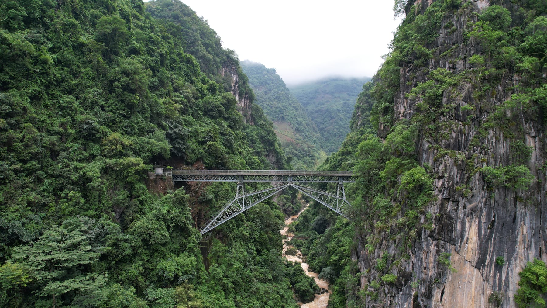 The Renzi Bridge on the Yunnan–Vietnam Railway, a steel arch spanning a forested gorge in Pingbian