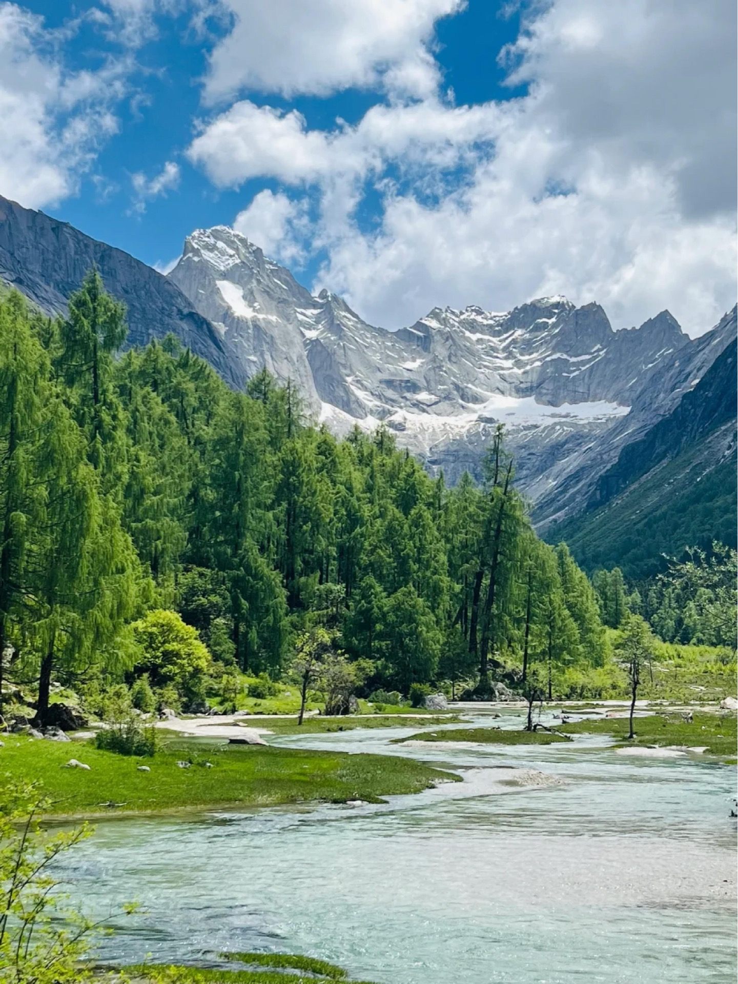 The Four Sisters rise above a turquoise glacial river on the Changping approach