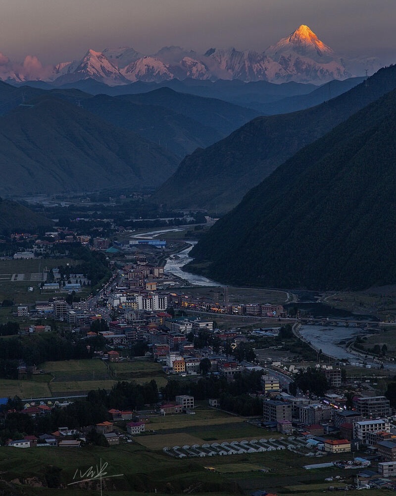 Mt Gongga catches pink alpenglow at dawn above Xinduqiao's grasslands, West Sichuan