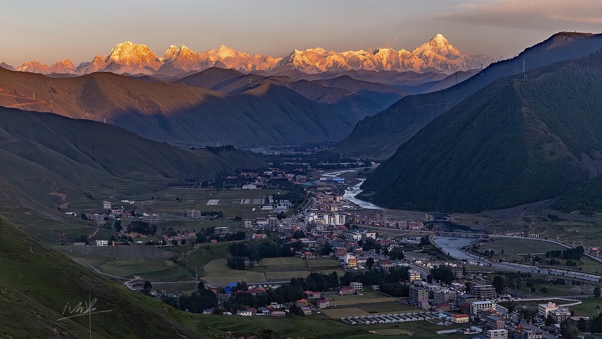 Layered valley light at Xinduqiao — rays raking across plateau meadow at dusk