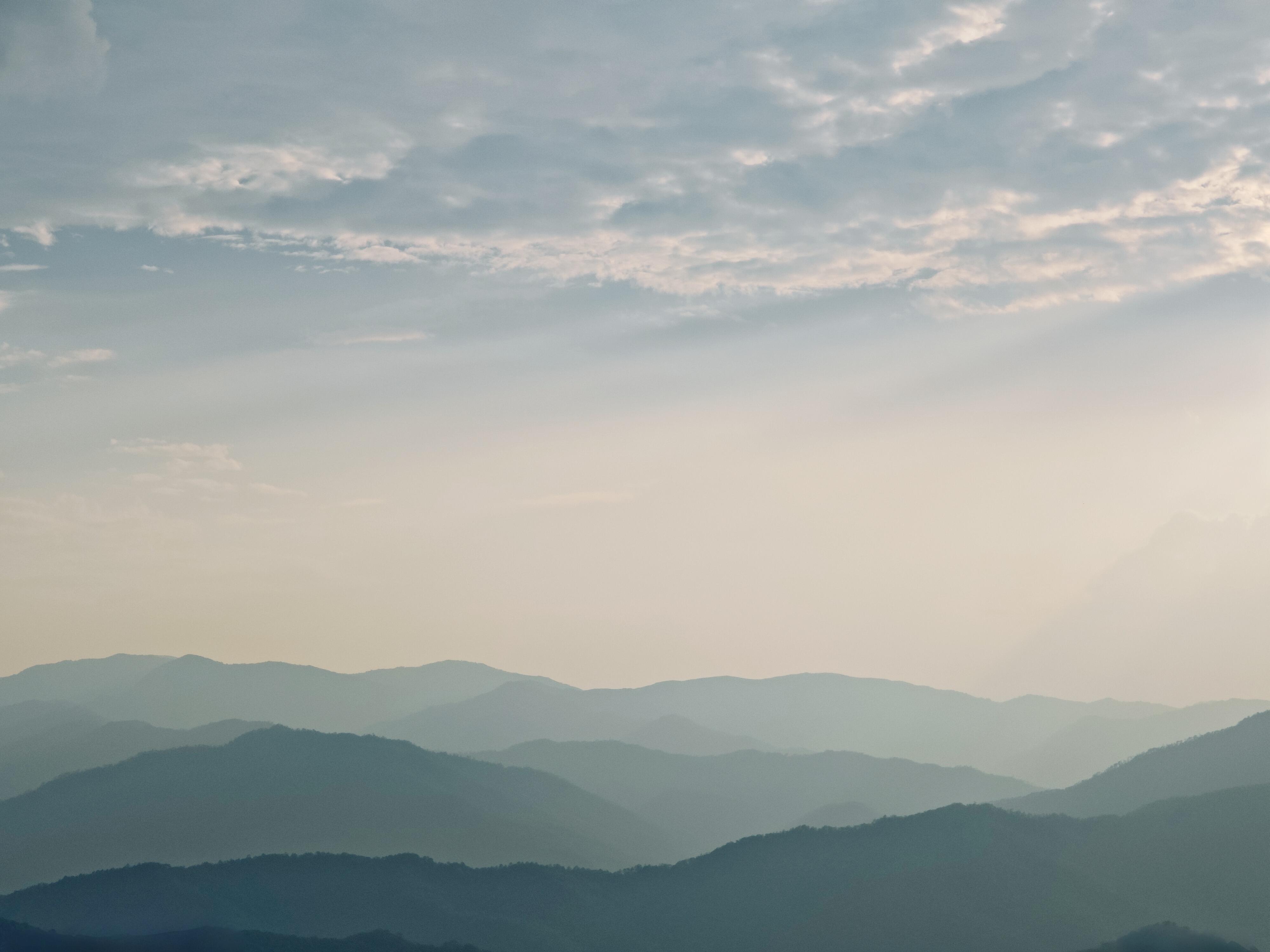 Layered Jingmai mountain ridges fading into pastel mist — the UNESCO Bulang tea-forest landscape, hero image for the Yunnan Living Heritage experience by Boutique China
