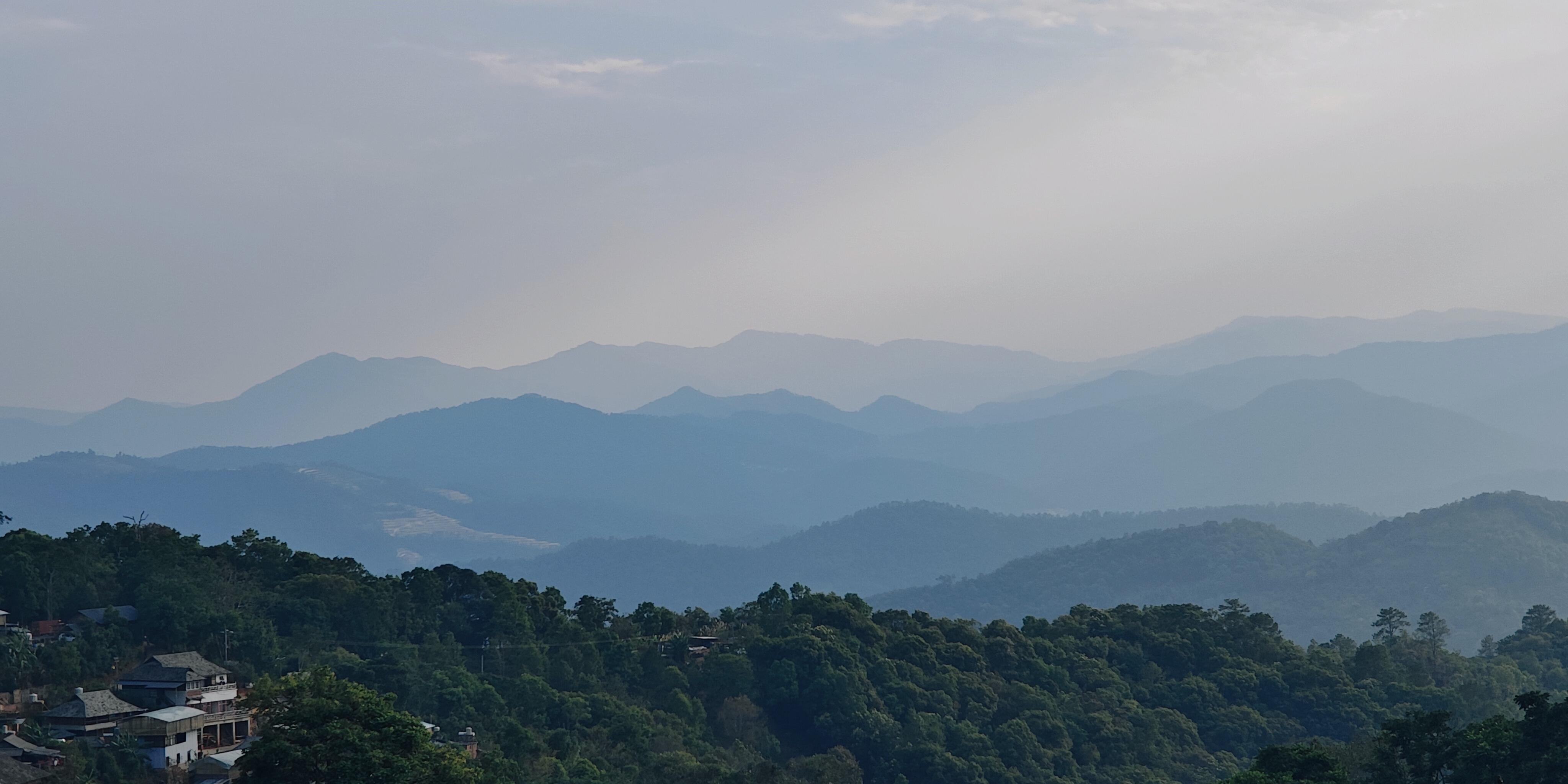 Bulang village rooftops below Jingmai mountain ridges fading into pastel twilight — the UNESCO tea-forest landscape, Living Heritage hero image