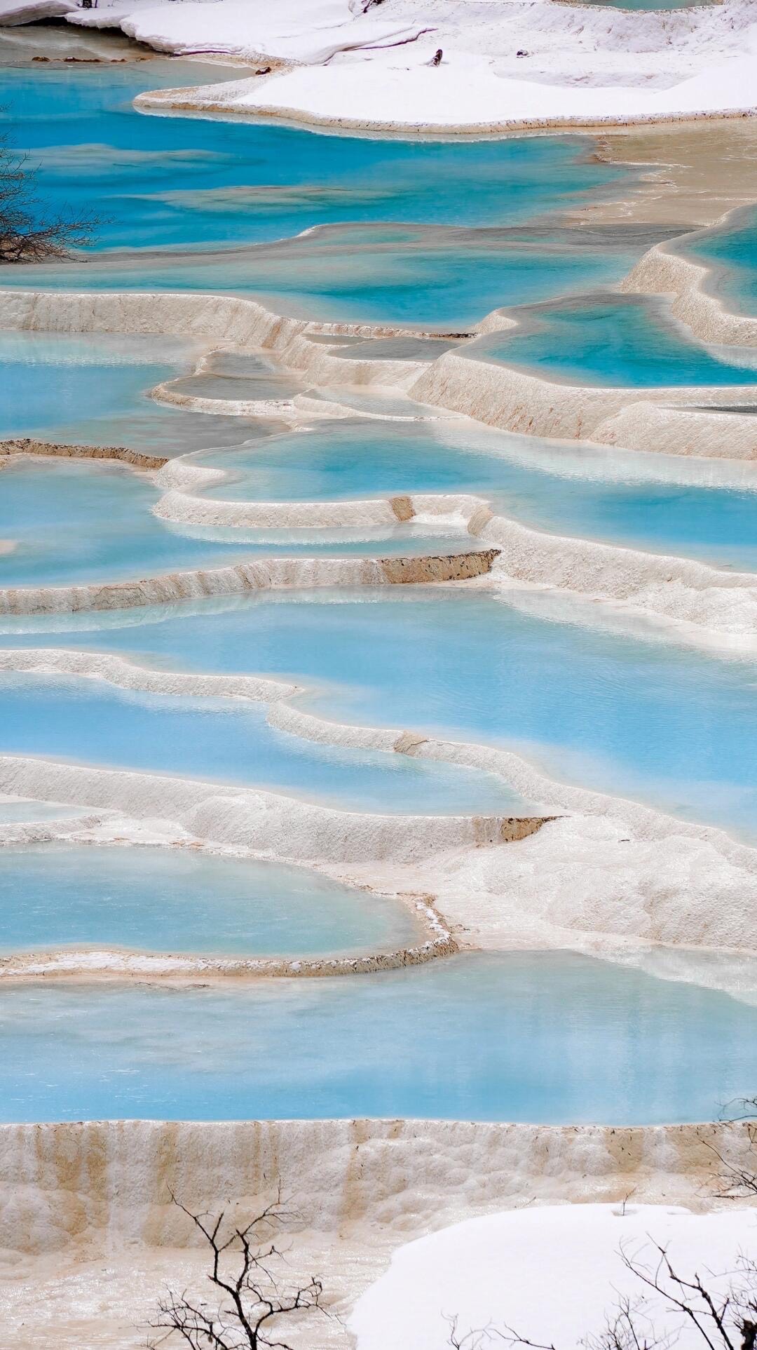 Winter at Huanglong — snow-dusted calcium terraces and vivid blue mineral pools
