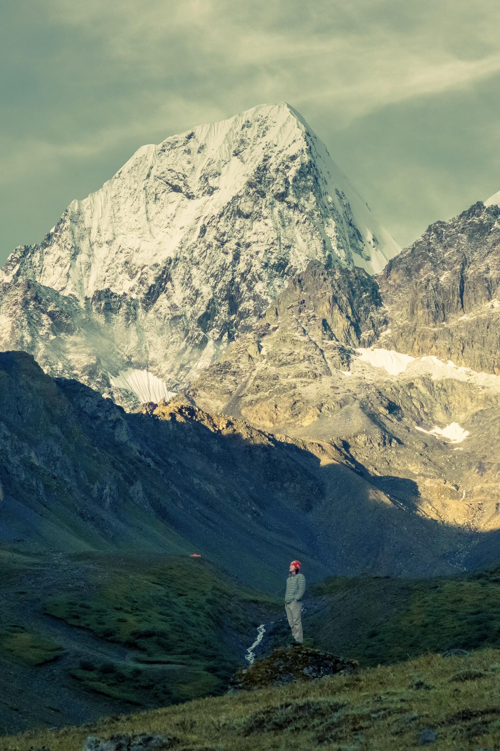 Close-up of Meili's north face with a lone hiker for scale — Day 2 evening light from Feilai Si direction
