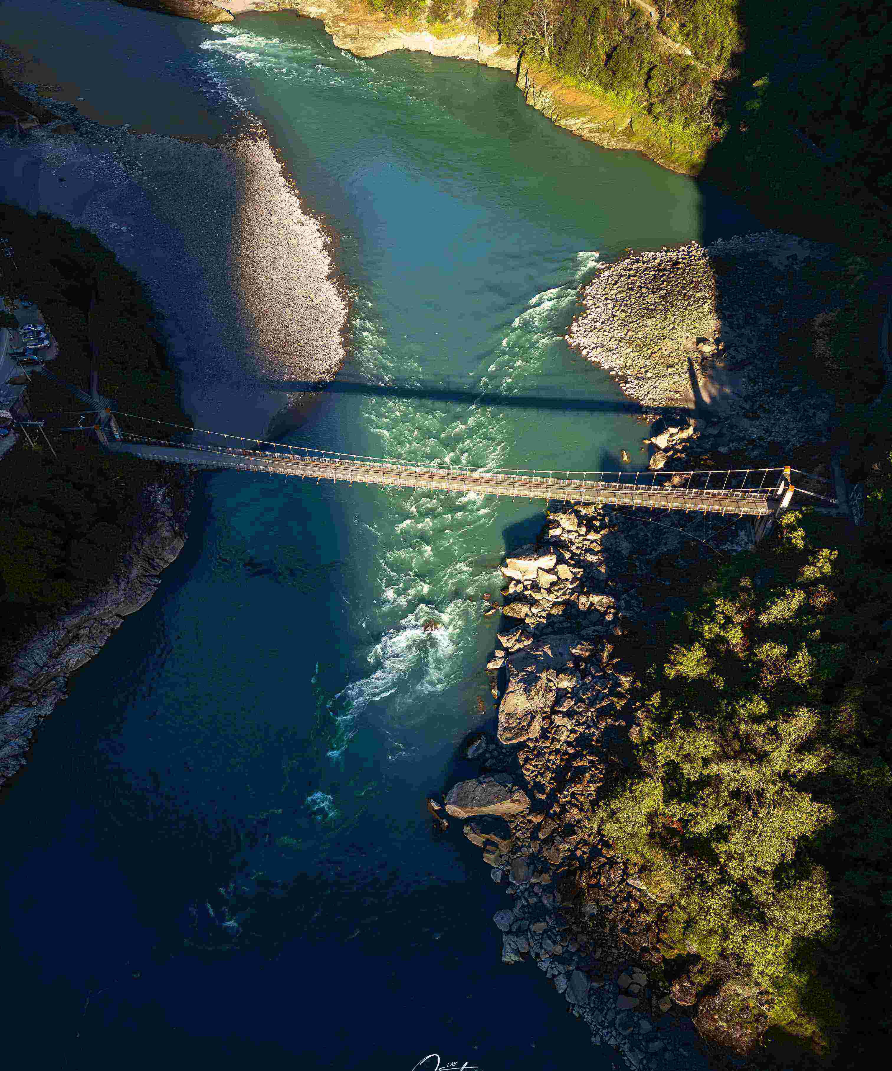 Single-span suspension bridge crossing the jade-green Salween between pale boulder banks