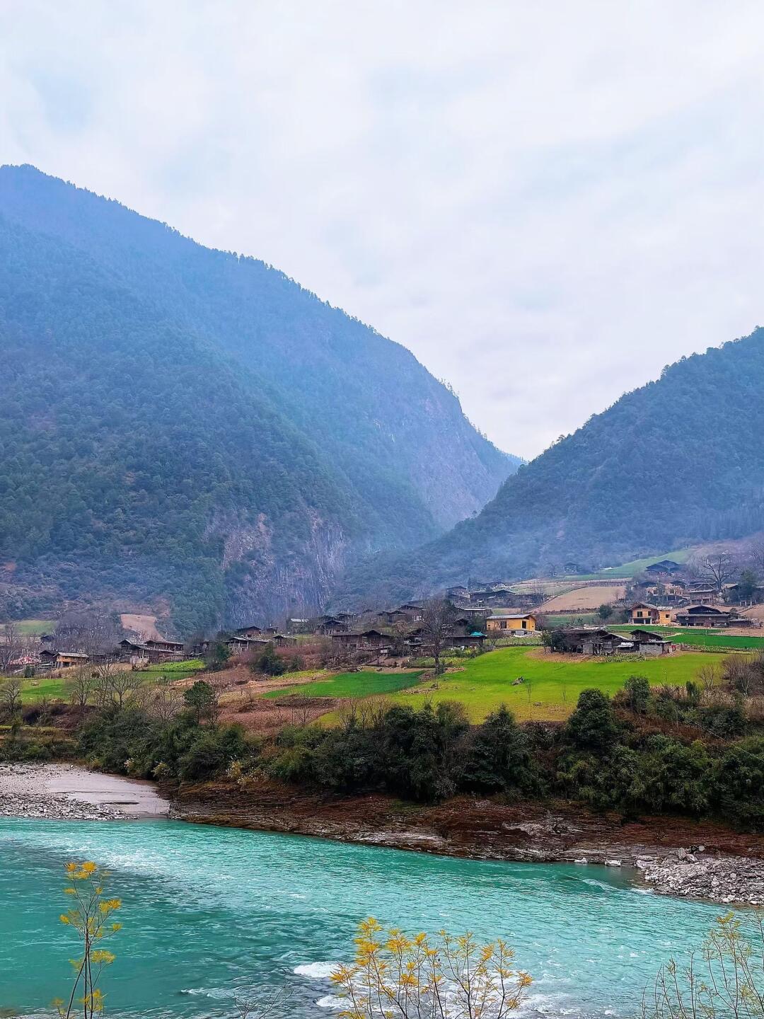Deep Nujiang gorge with turquoise river threading between steep forested canyon walls