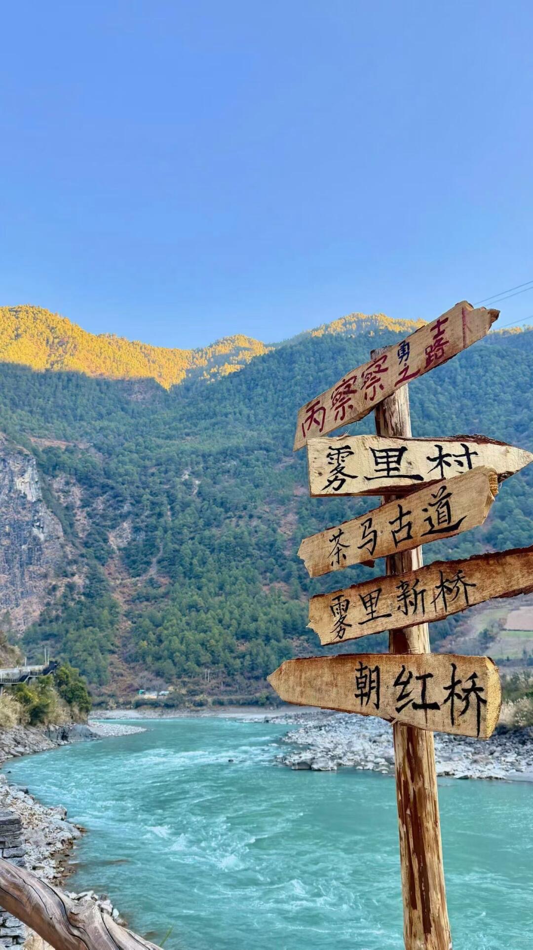 Wooden Salween River signpost above the turquoise Nujiang canyon in golden light