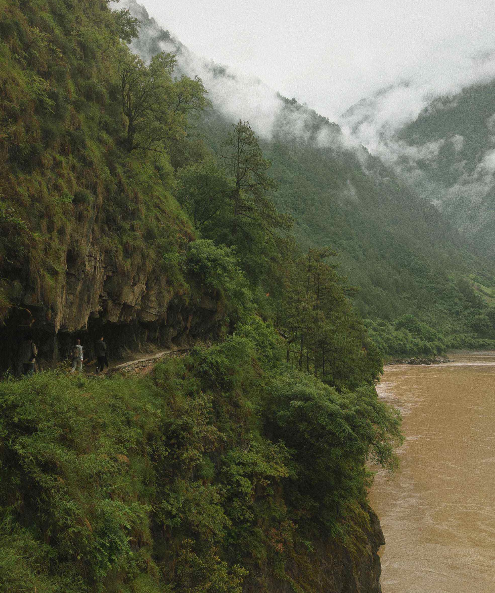 The Wuli cliff trail above a misty Nujiang gorge with the turquoise river cutting through