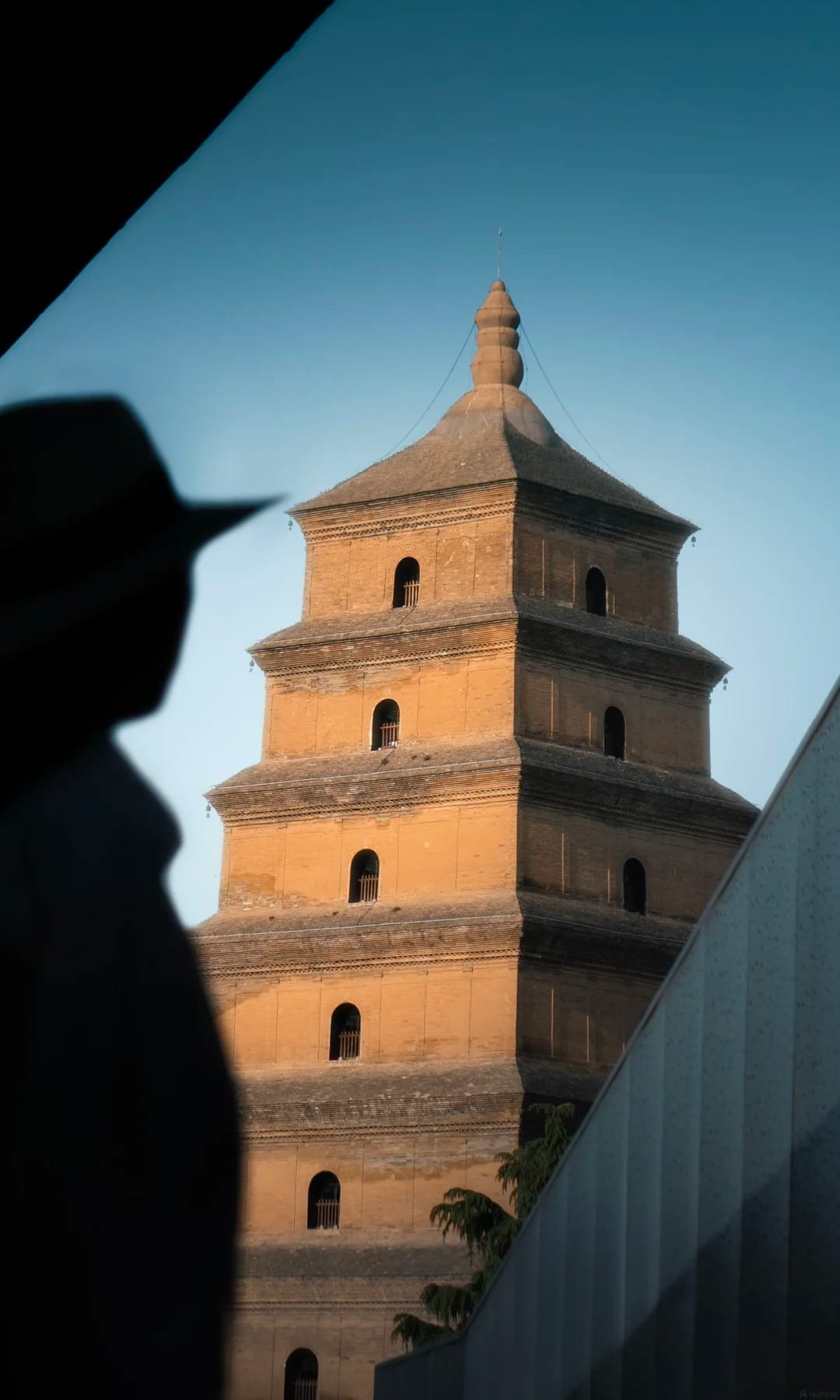 The Big Wild Goose Pagoda in golden-hour light beside a silhouetted figure, Xi'an