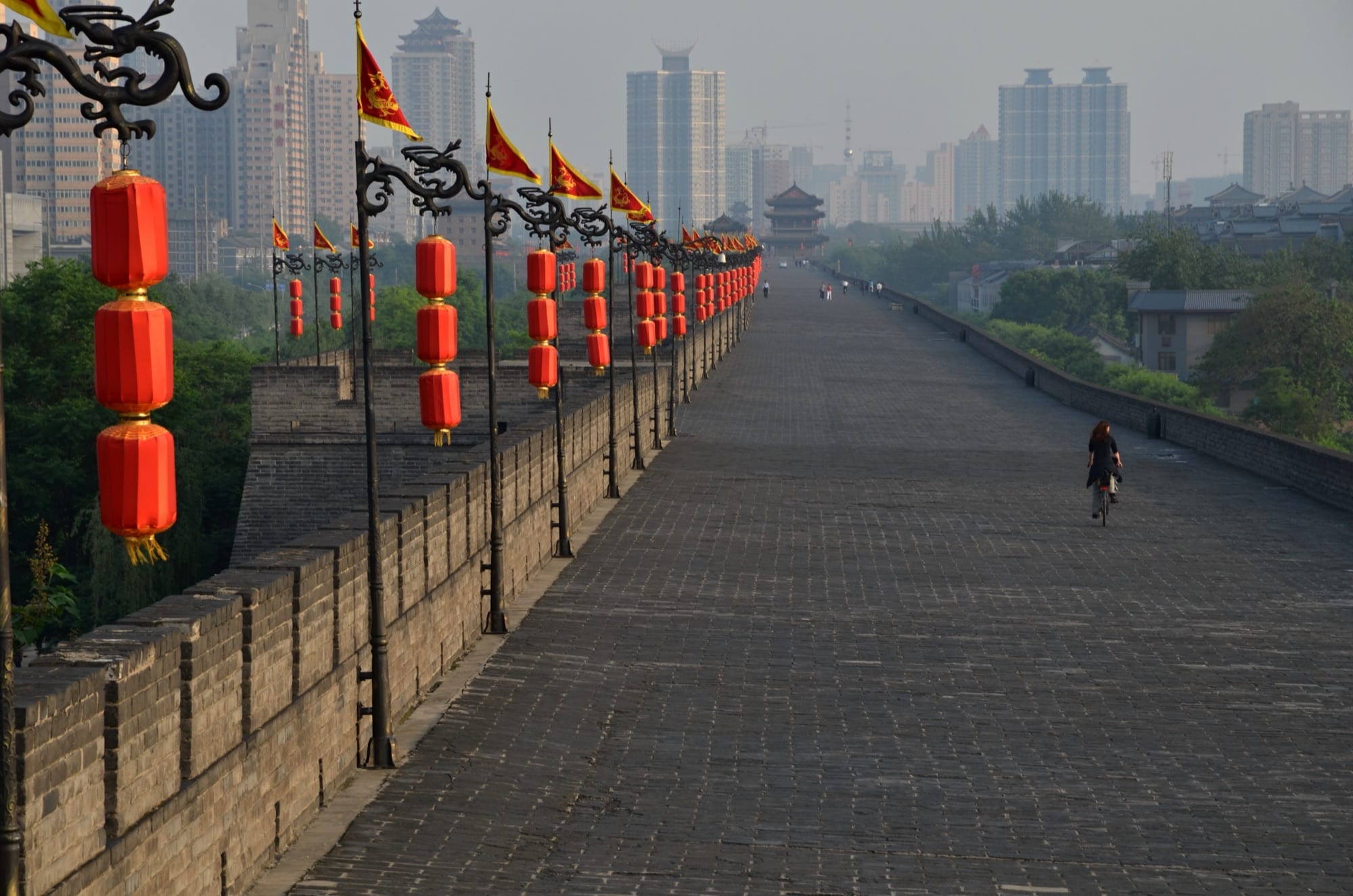 A cyclist riding the broad top of Xi'an's city wall past rows of red lanterns