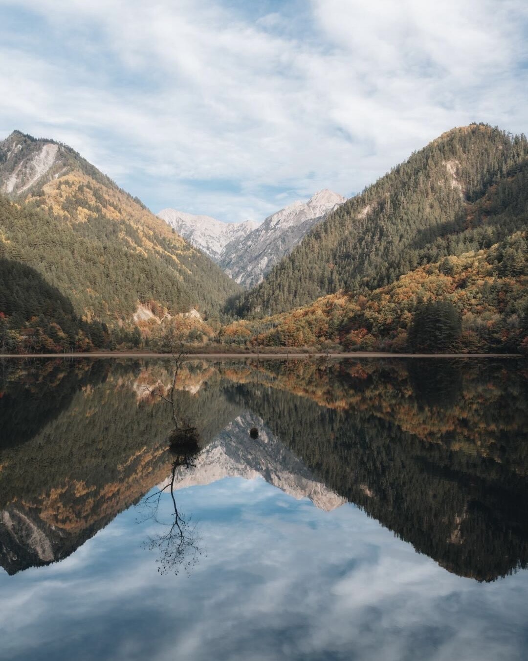 Mirror Lake in Jiuzhai Valley reflecting autumn forests and distant snow peaks