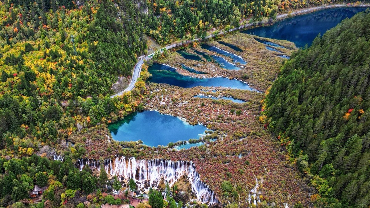 Aerial view of turquoise cascade pools and waterfalls amid autumn forest in Jiuzhai Valley