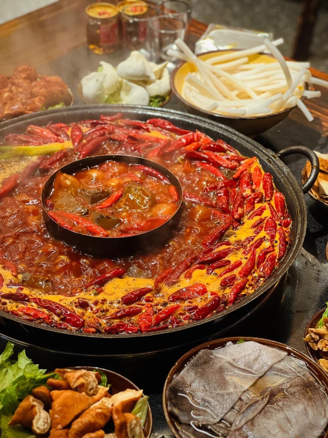 A classic Chongqing hotpot — chili ring around the rim, ingredients laid out on the wooden table