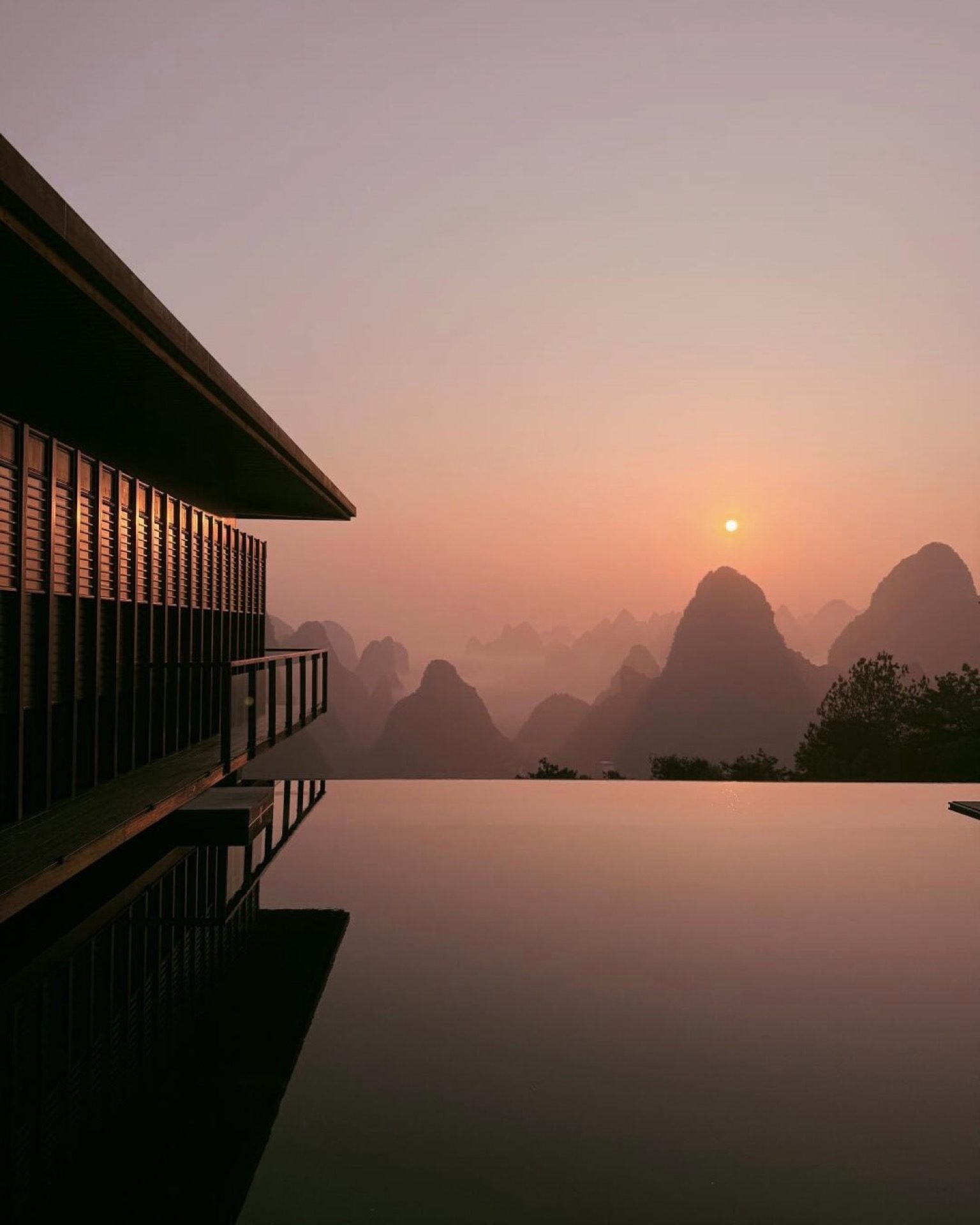Huashan Yunshe resort infinity pool at dusk with karst peaks glowing in the last light, Yangshuo — Guilin private tour