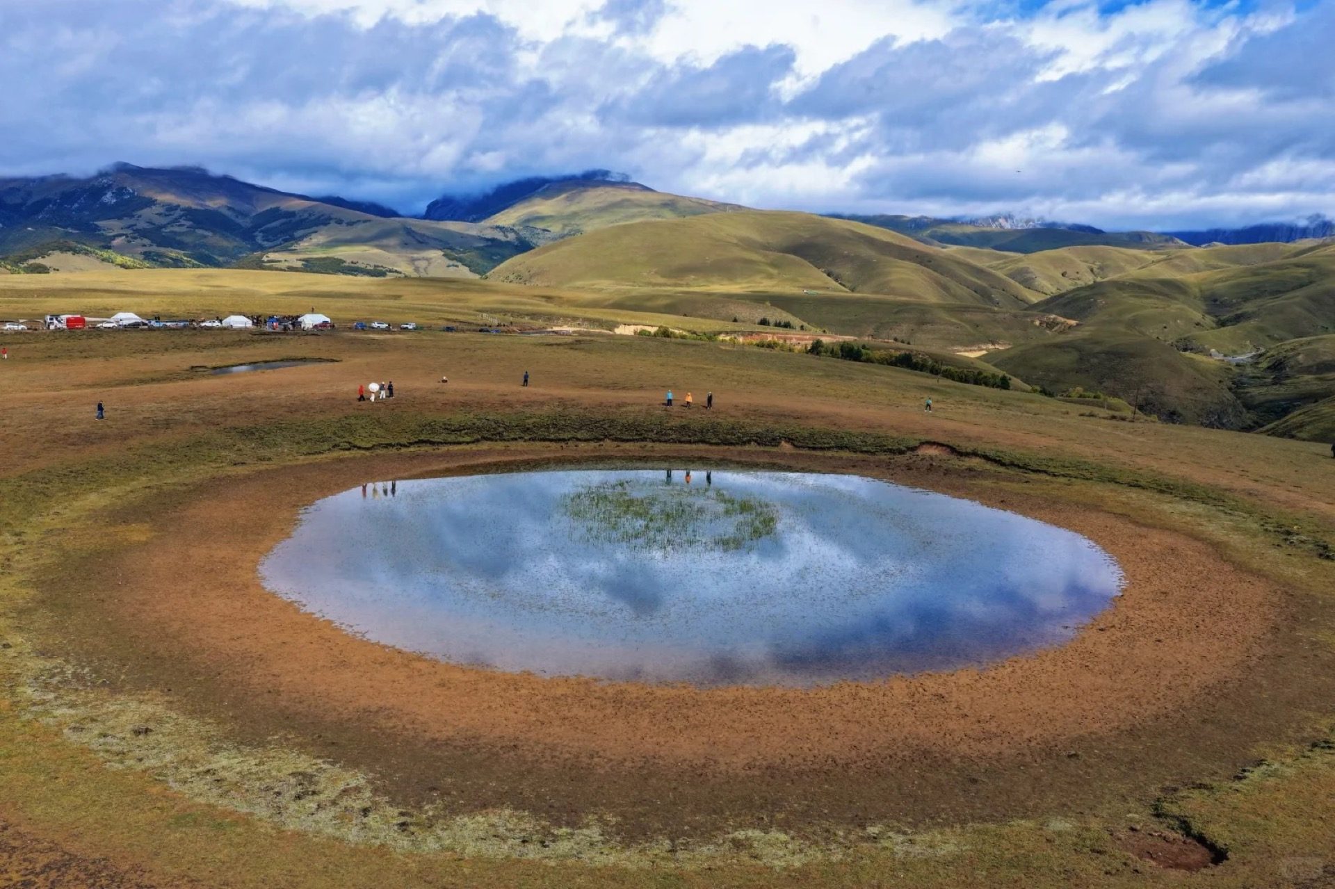 Eye of the Genie — circular sacred pond ringed by Litang's high grassland with distant rolling ridges, hero image for the Sacred Peaks Sichuan private tour by Boutique China