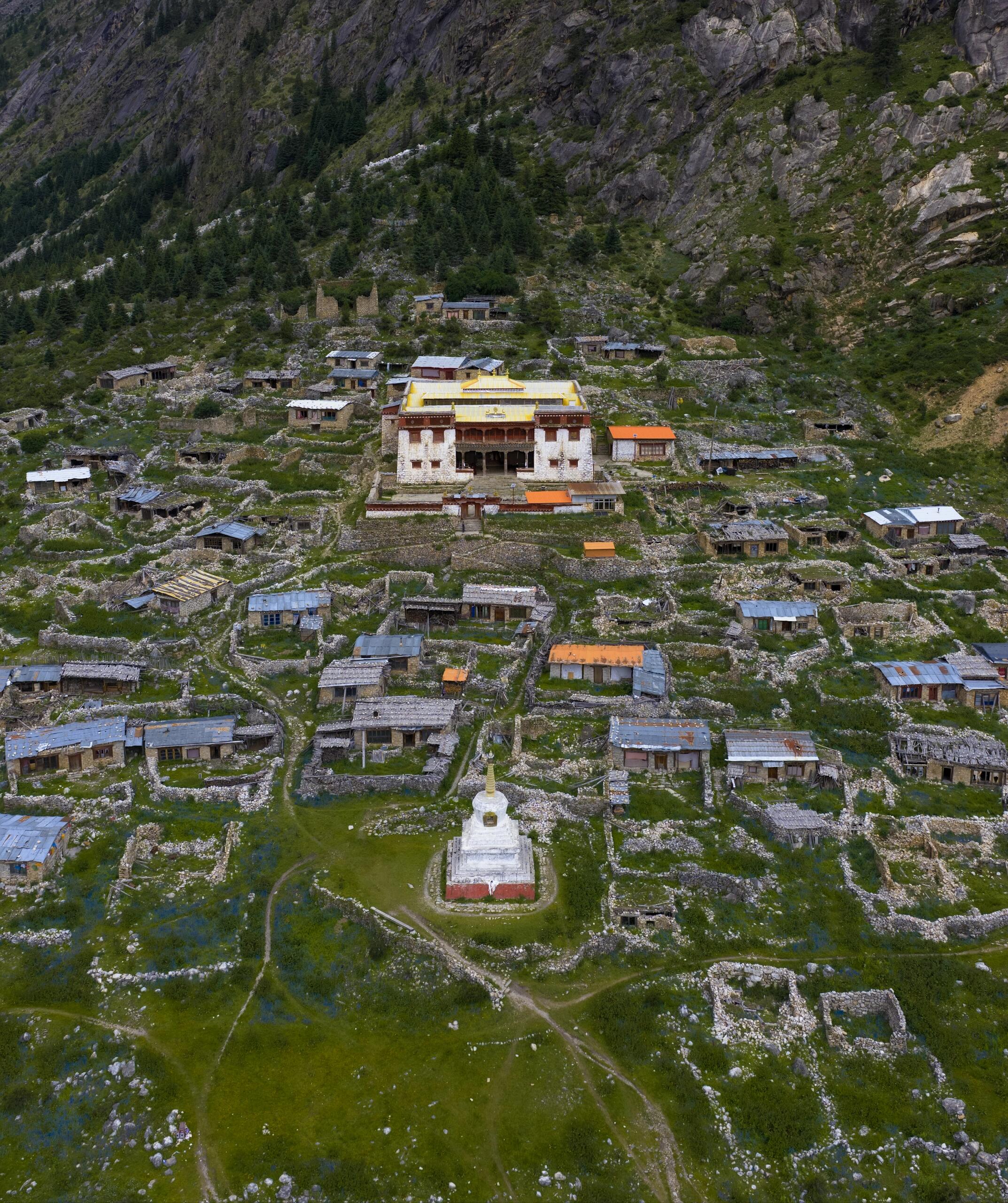 Aerial over Leng-Gu Temple and its ancient stone village — red-tiled gompa, white stupa, stone-walled houses