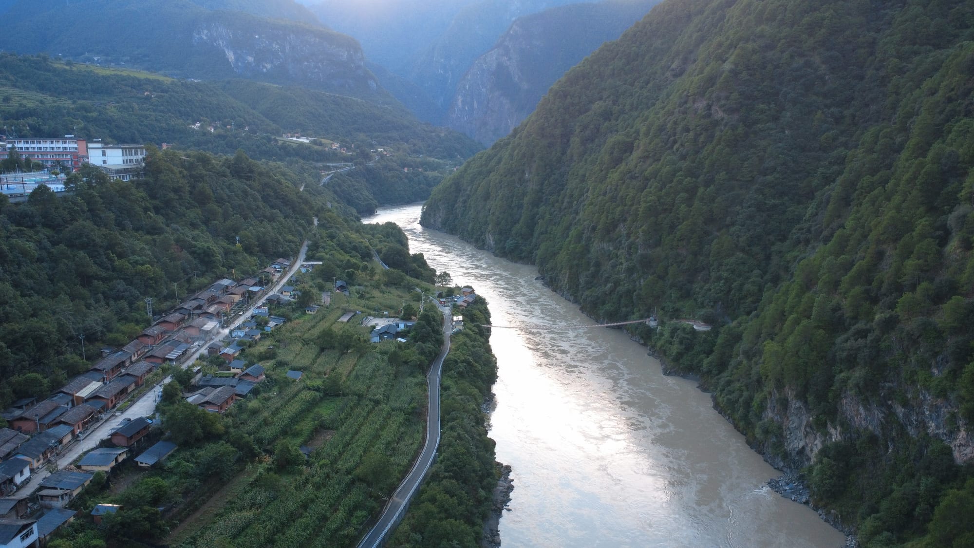 A village on the river at the foot of the gorge walls in the last light, Deqin — Shangri-La Wine Journey