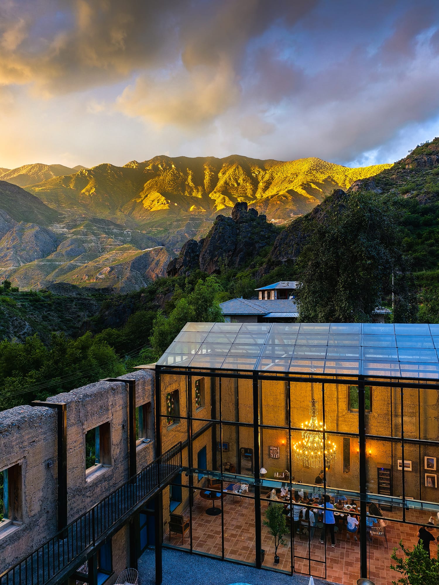 Zuishengmeng's rammed-earth winery lodge and its glass pavilion in Hachong village, the peaks above lit gold — Shangri-La Wine Journey