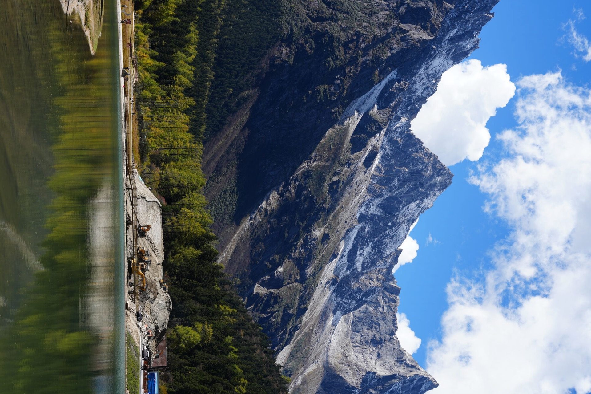 Emerald lake beneath a sheer cliff face in Bipenggou Valley