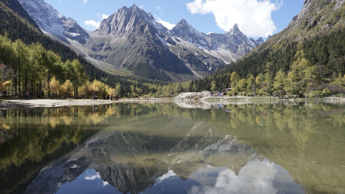 Snow peaks reflected in a mirror-still alpine lake at Bipenggou, West Sichuan