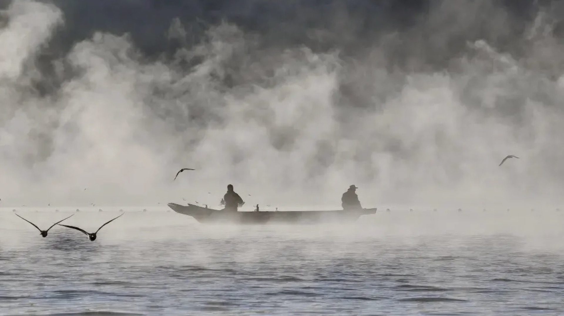 Fisherman casting nets on misty Lugu Lake at dawn