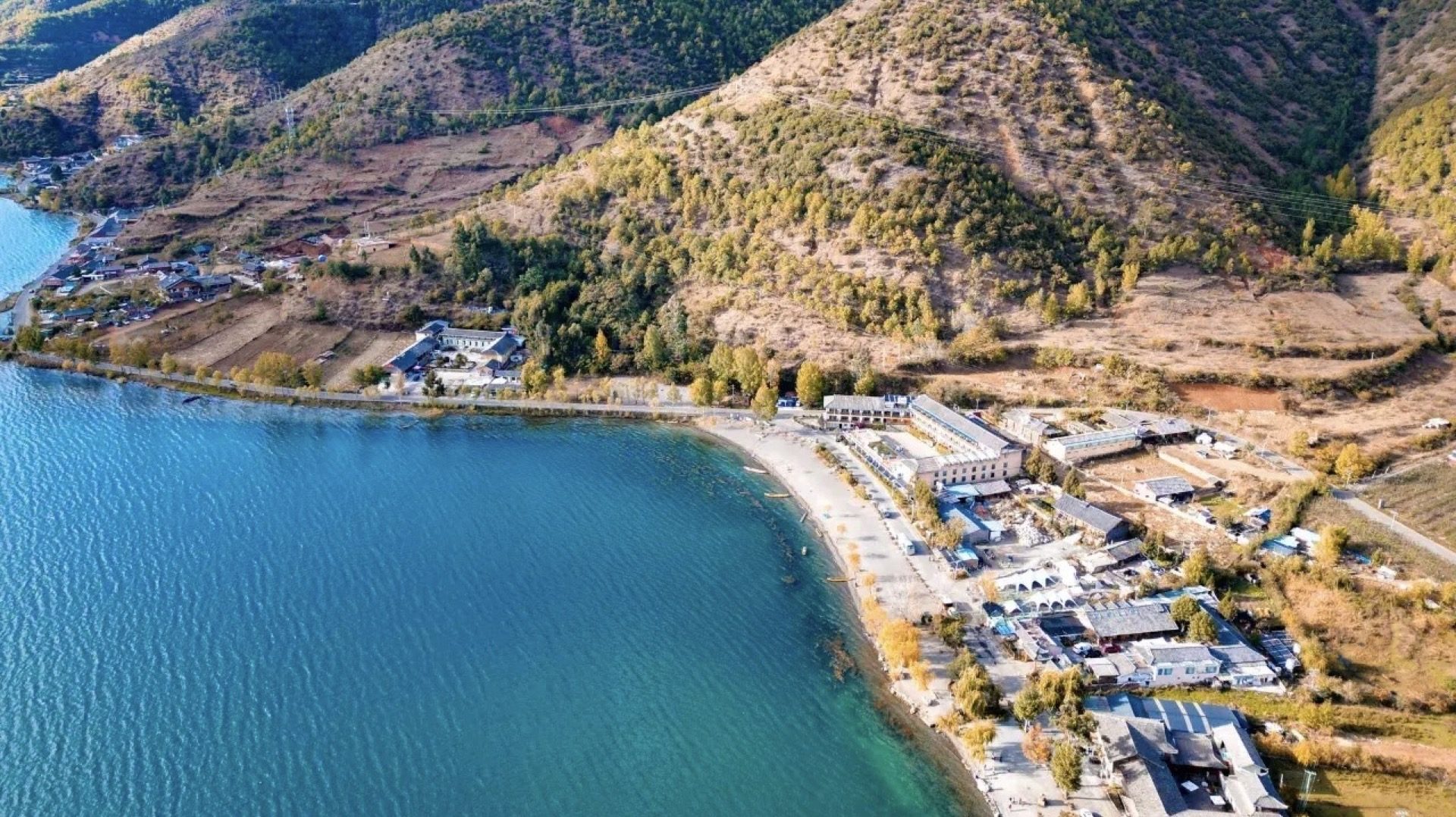 Aerial view of Lugu Lake's sapphire shoreline and forested ridges