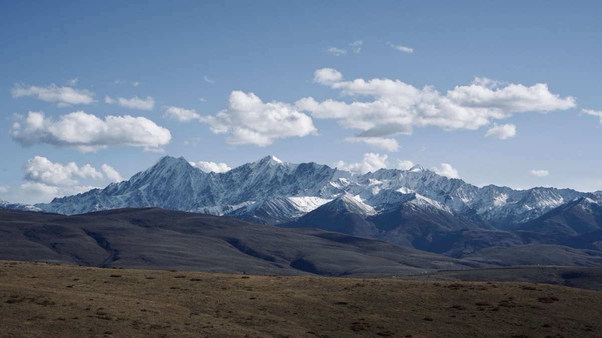 West Sichuan's open Tibetan grasslands meeting a distant snow-capped range