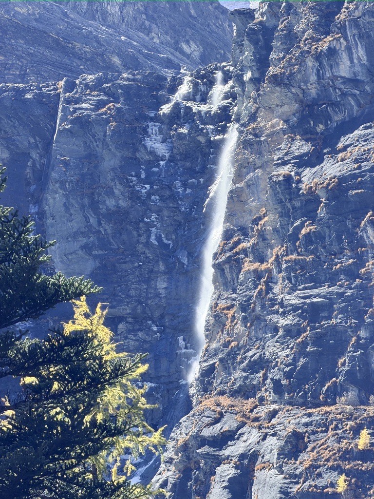 High cliff waterfall threading down a sheer granite face in Daocheng Yading