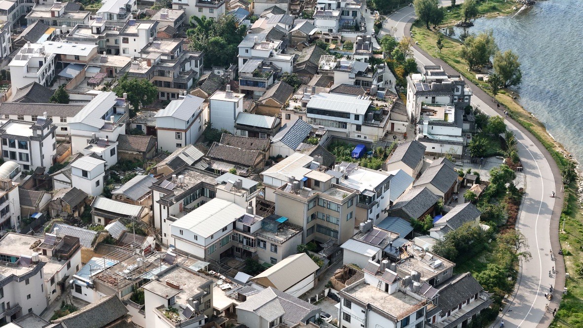 Aerial of a Dali Bai village stretching along Erhai Lake's shoreline road