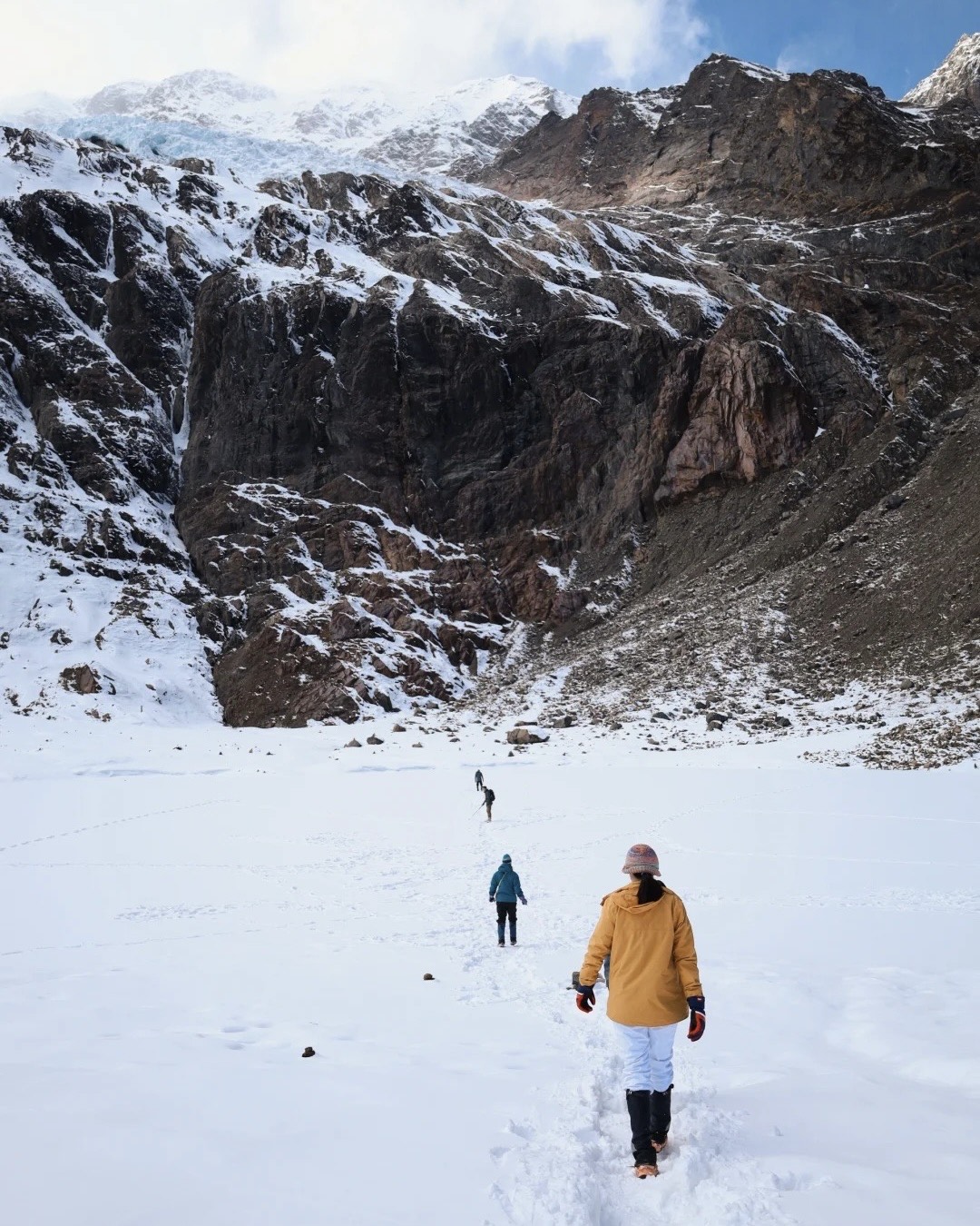 Hikers crossing a snowfield below Niru's glacier cirque on a Shangri-La alpine trek