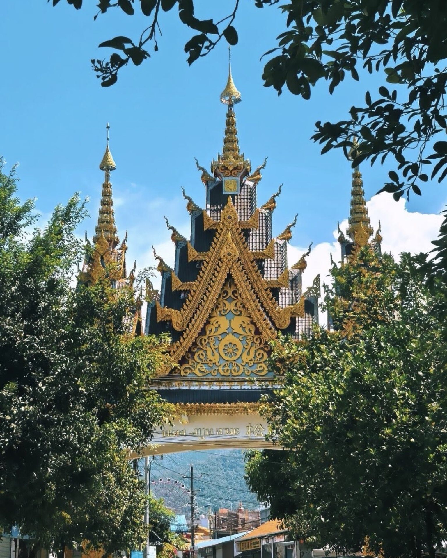 Ornate Dai temple gate with gilded carvings and spire finials at a Mangshi pagoda — Yunnan slow culture tour