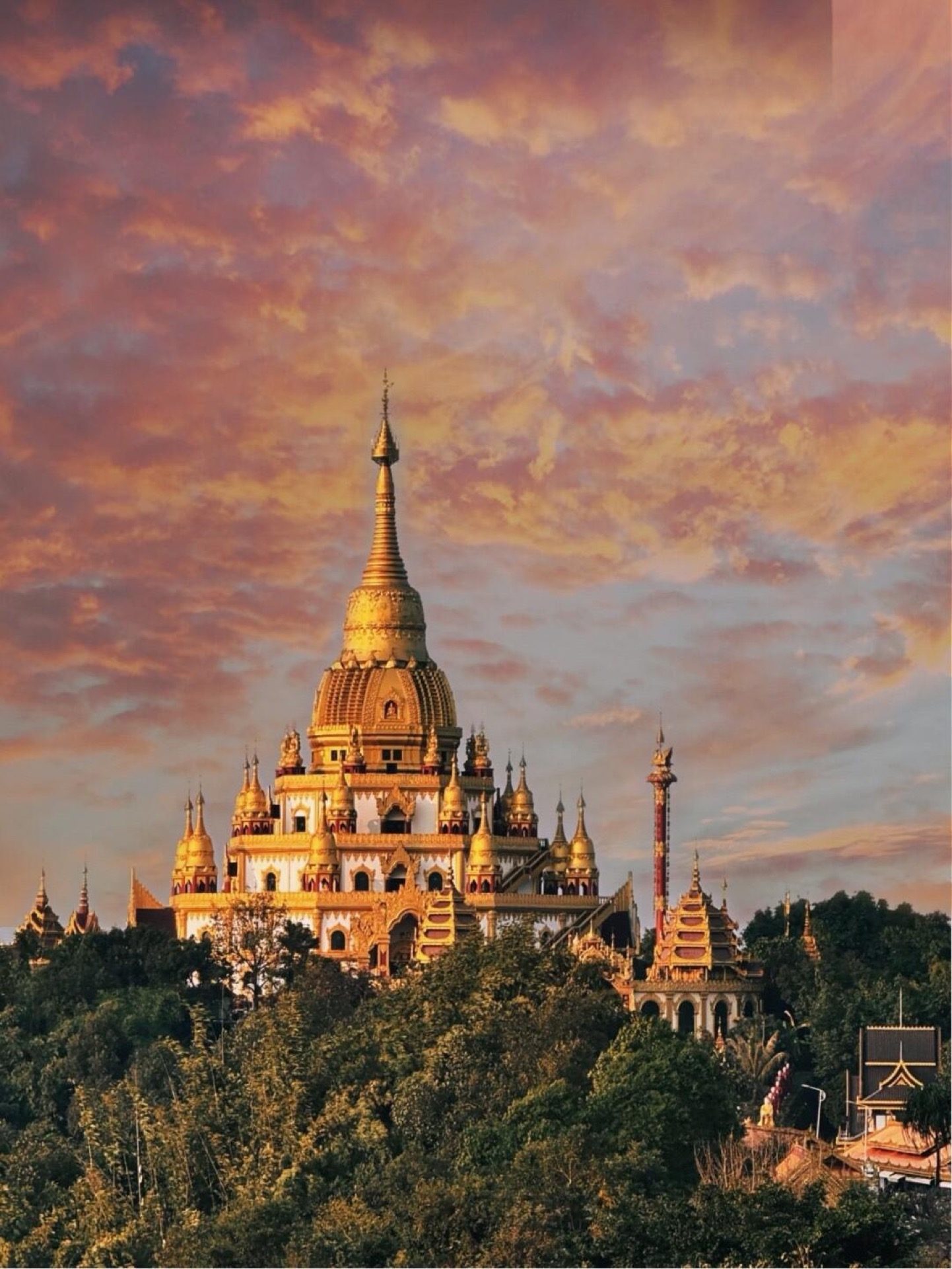 Golden pagoda on a Mangshi hilltop against a pink evening sky — Yunnan slow culture tour