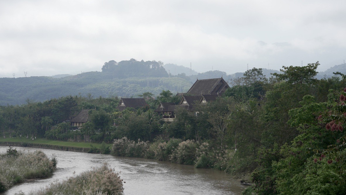 Traditional Dai-style houses along a misty river in Xishuangbanna, southern Yunnan