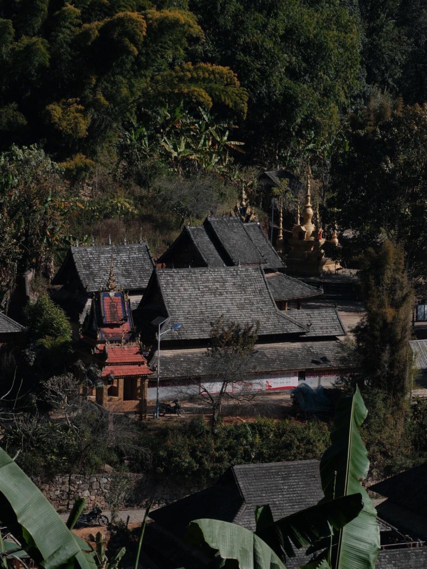 Ancient Mengben temple standing among old trees in a Jingmai Mountain village — Yunnan tropical tour