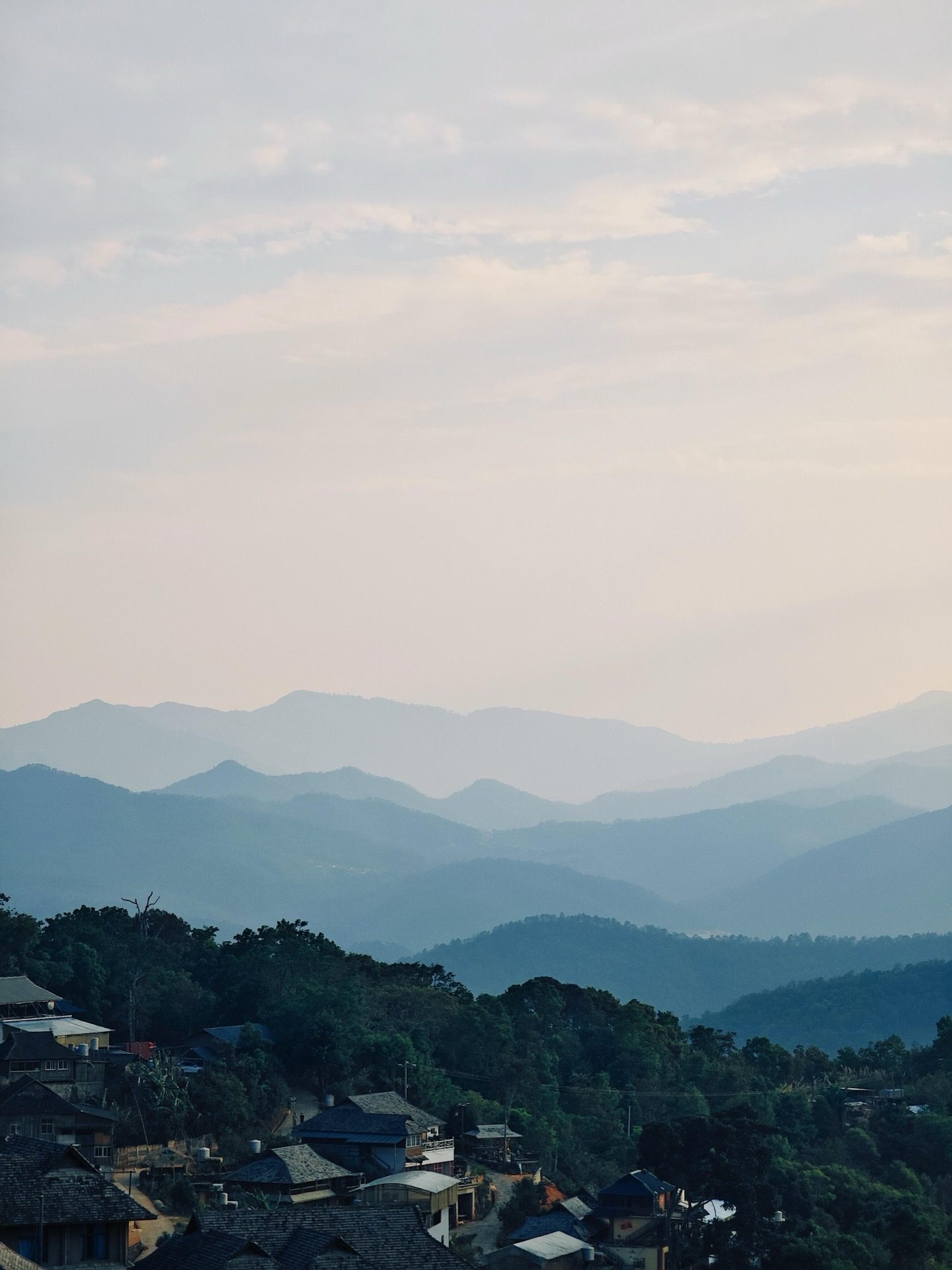 Layered ridges of Jingmai Mountain receding into the mist — the ancient tea landscape from the approach road