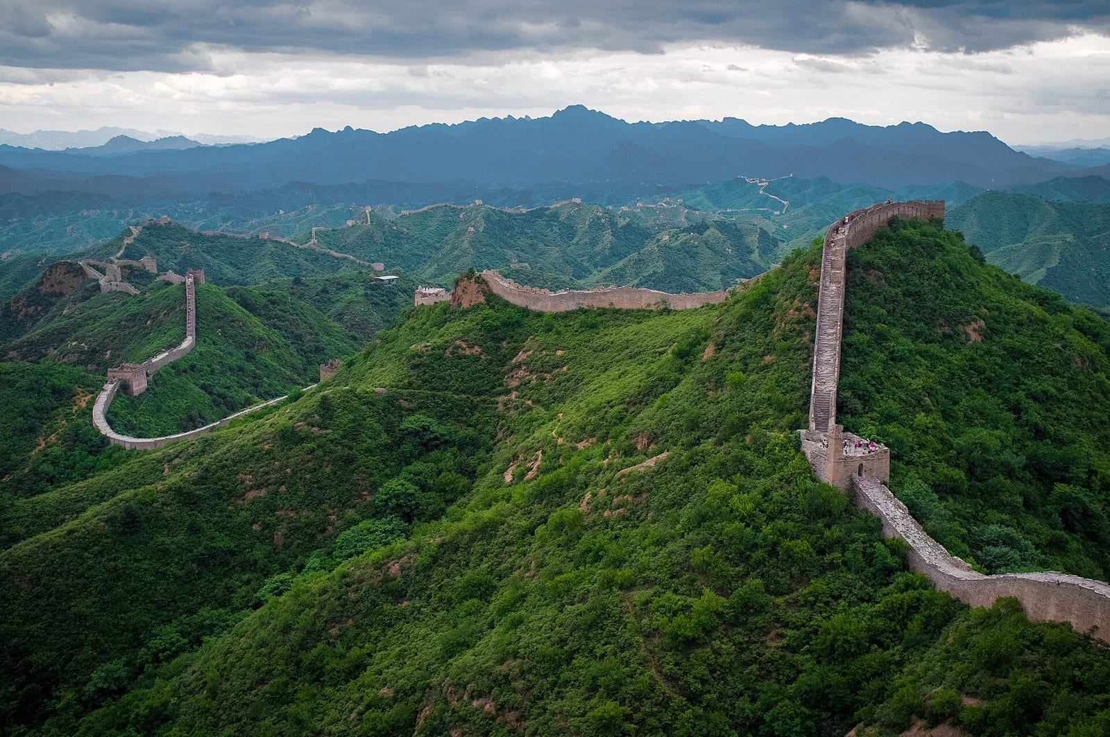 The Great Wall at Jinshanling snaking along a green ridge under storm light