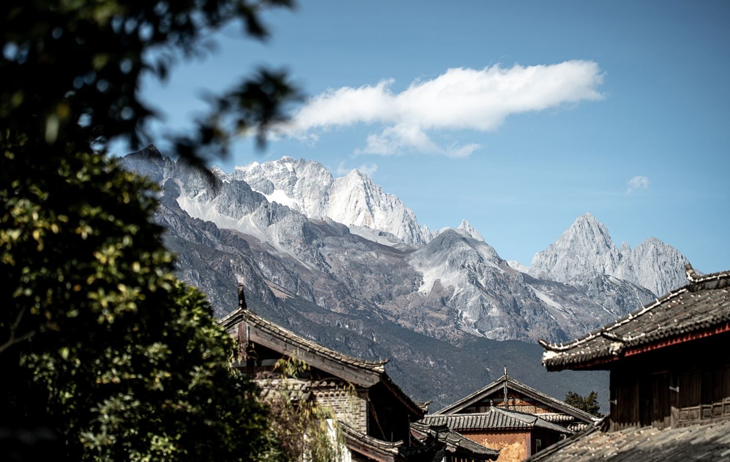 Jade Dragon Snow Mountain's snow-streaked peaks over the tiled roofs of Lijiang Old Town.