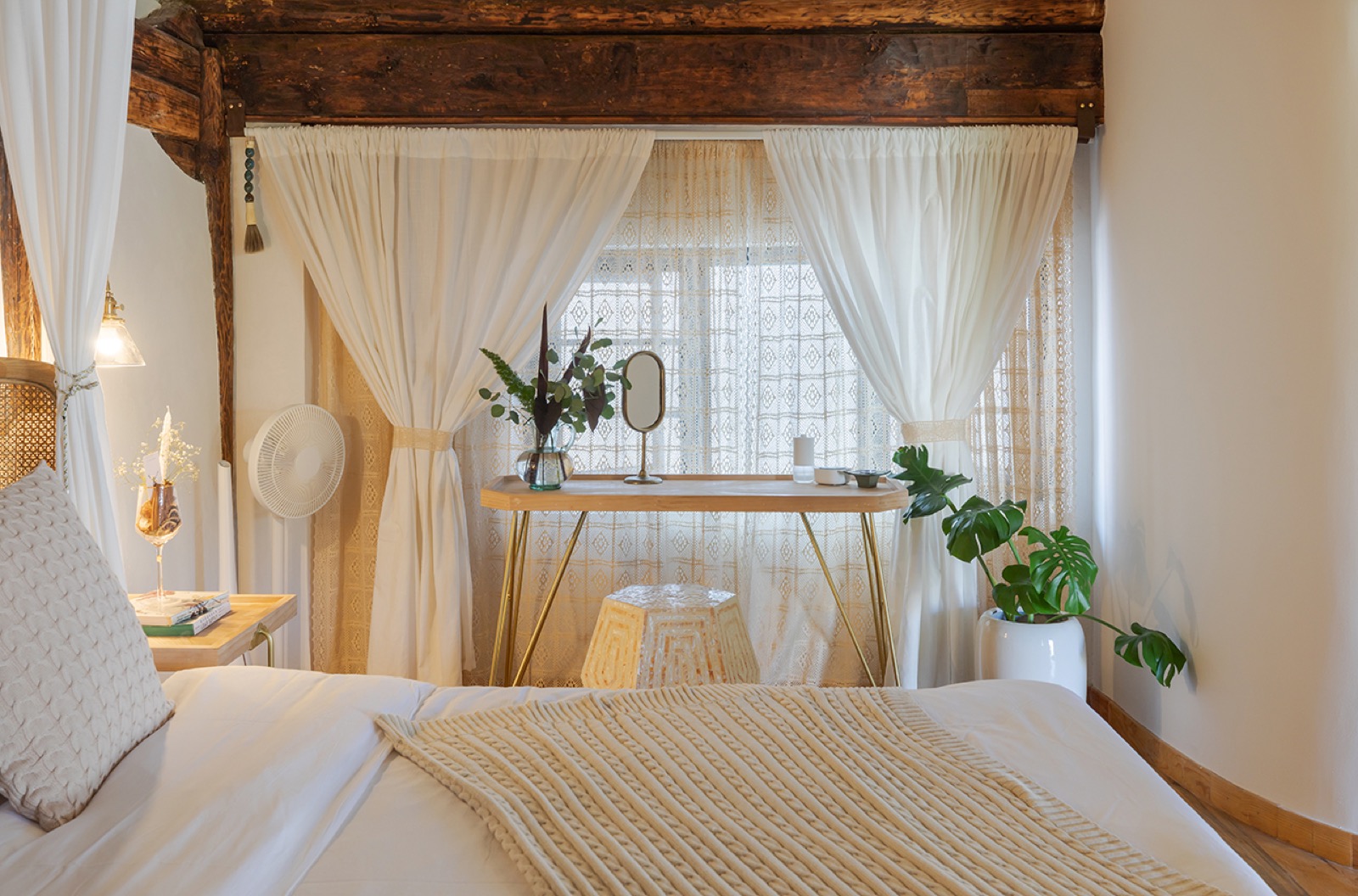 Banxia Garden — a guest room with dark timber roof beams, a canopy bed and cane headboard against whitewashed walls, Xizhou