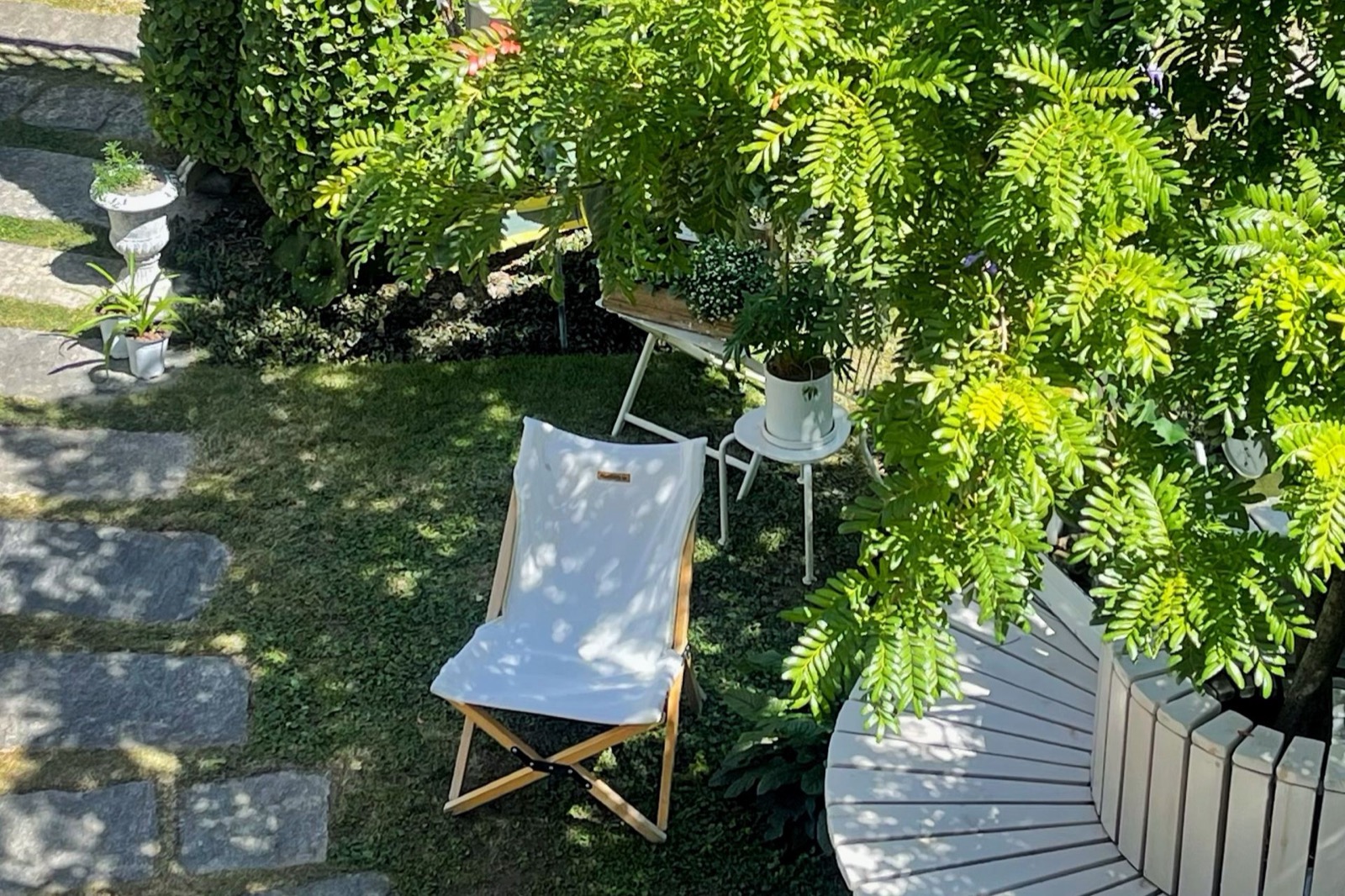 Banxia Garden — a canvas sling chair on a mossy lawn under a shade tree in the planted courtyard garden, Xizhou