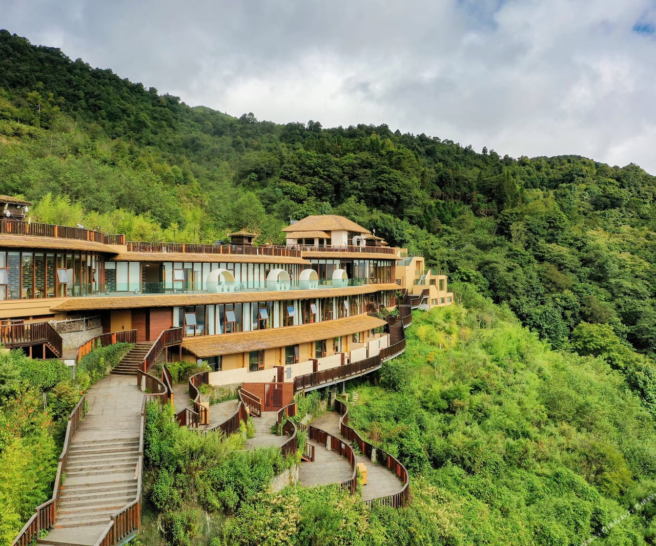 The curved, stepped wings of Duoyishu Half-Mountain set into the green hillside