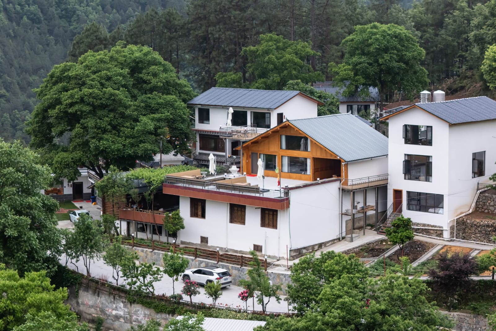 Jilin Mountain Lodge — the lodge compound on its wooded hillside in Chunduole, village houses and the road below