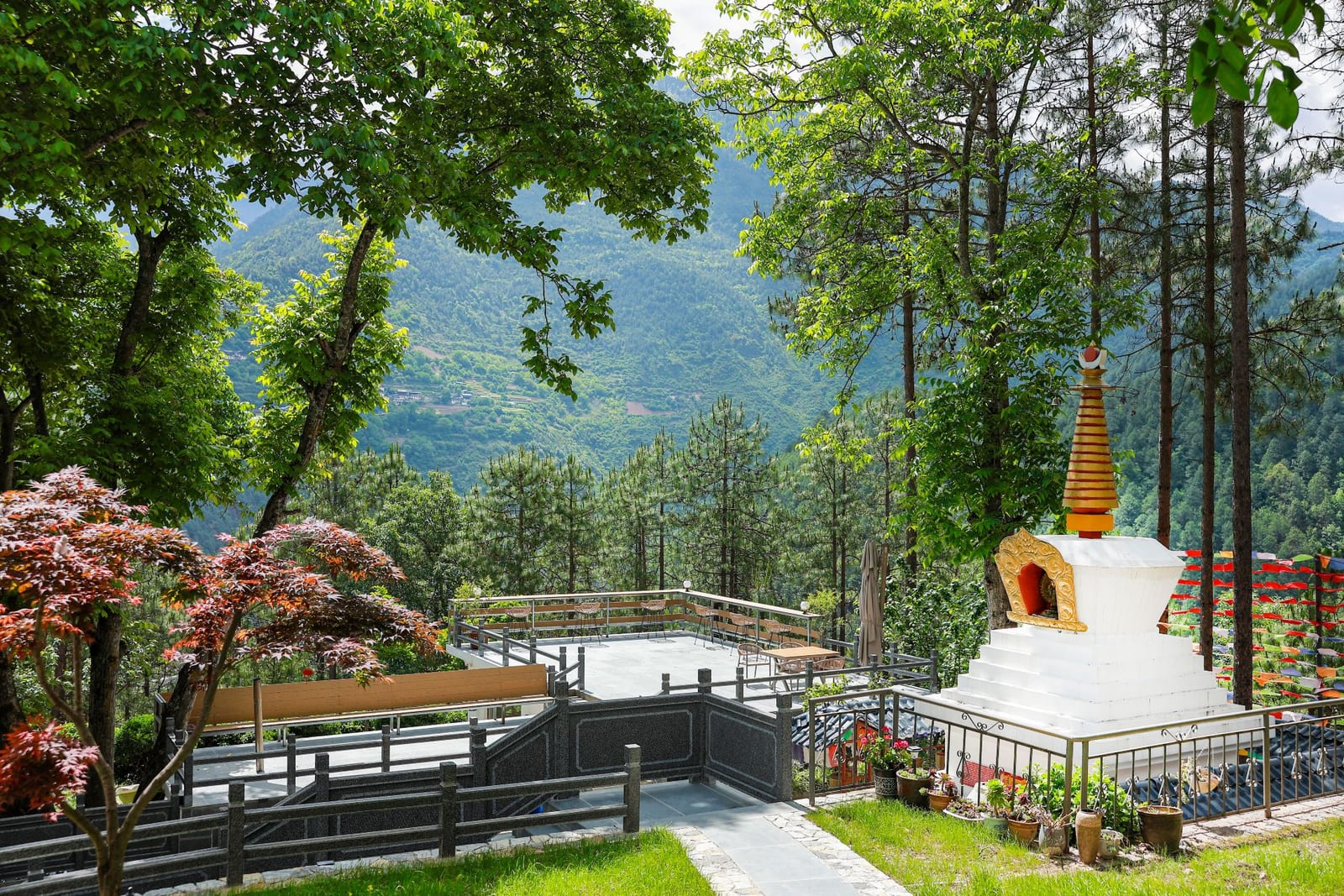 Jilin Mountain Lodge — a white stupa with a gold spire on the lodge terrace among pines and maples, the valley beyond